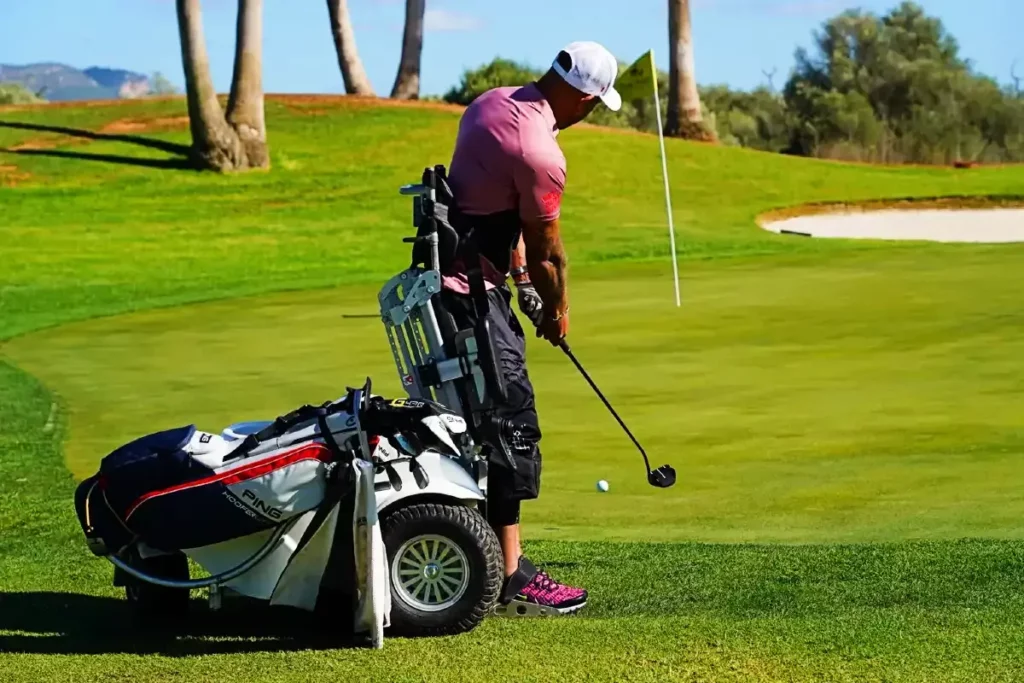 Golfer in a pink polo utilizing the ParaGolfer to stand and take a swing on the golf course.