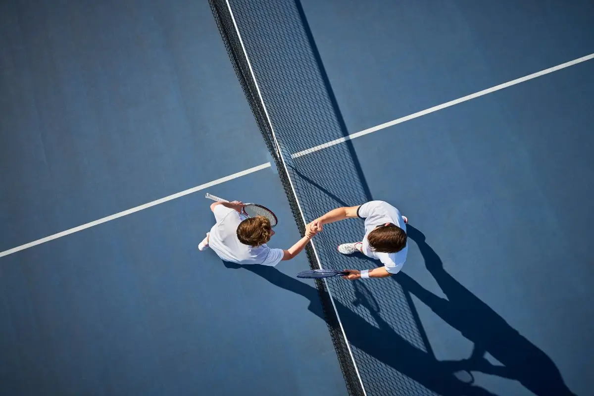 Aerial view of two players on a tennis court shaking hands after a match.